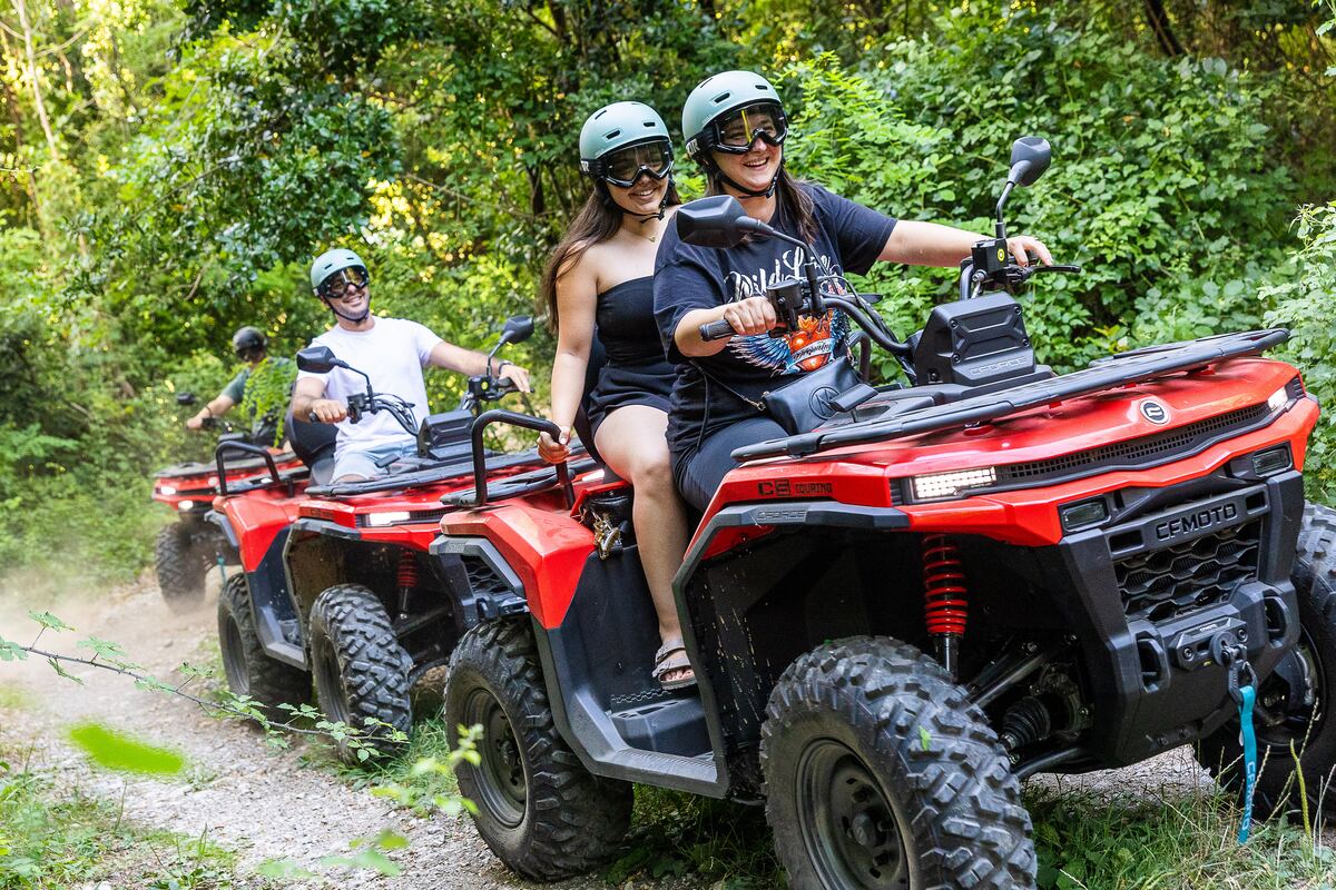 Dvije nasmijane vozačice dijele quad na šumskoj stazi