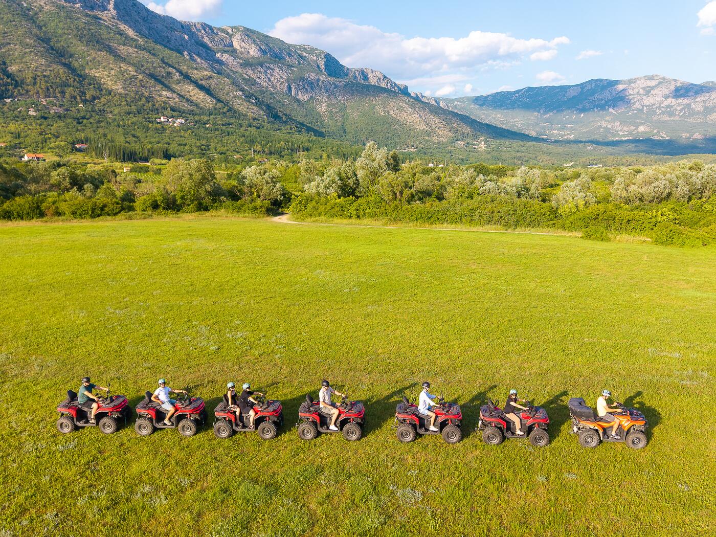 Red potpuno novih CF Moto quadova poredanih na livadi ispod planine
